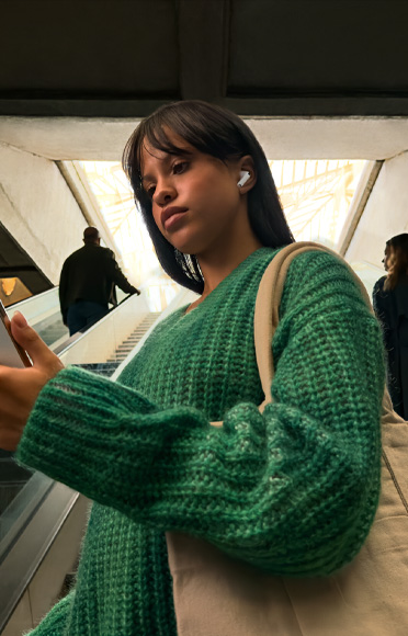 一个人戴着 AirPods Pro 3，正在看自己的 iPhone