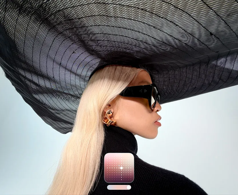 一张女子头戴黑色宽边帽饰的人像照，展示全新“珠光”摄影风格，可以为弱光环境下或使用夜间模式拍摄的照片提亮画面。